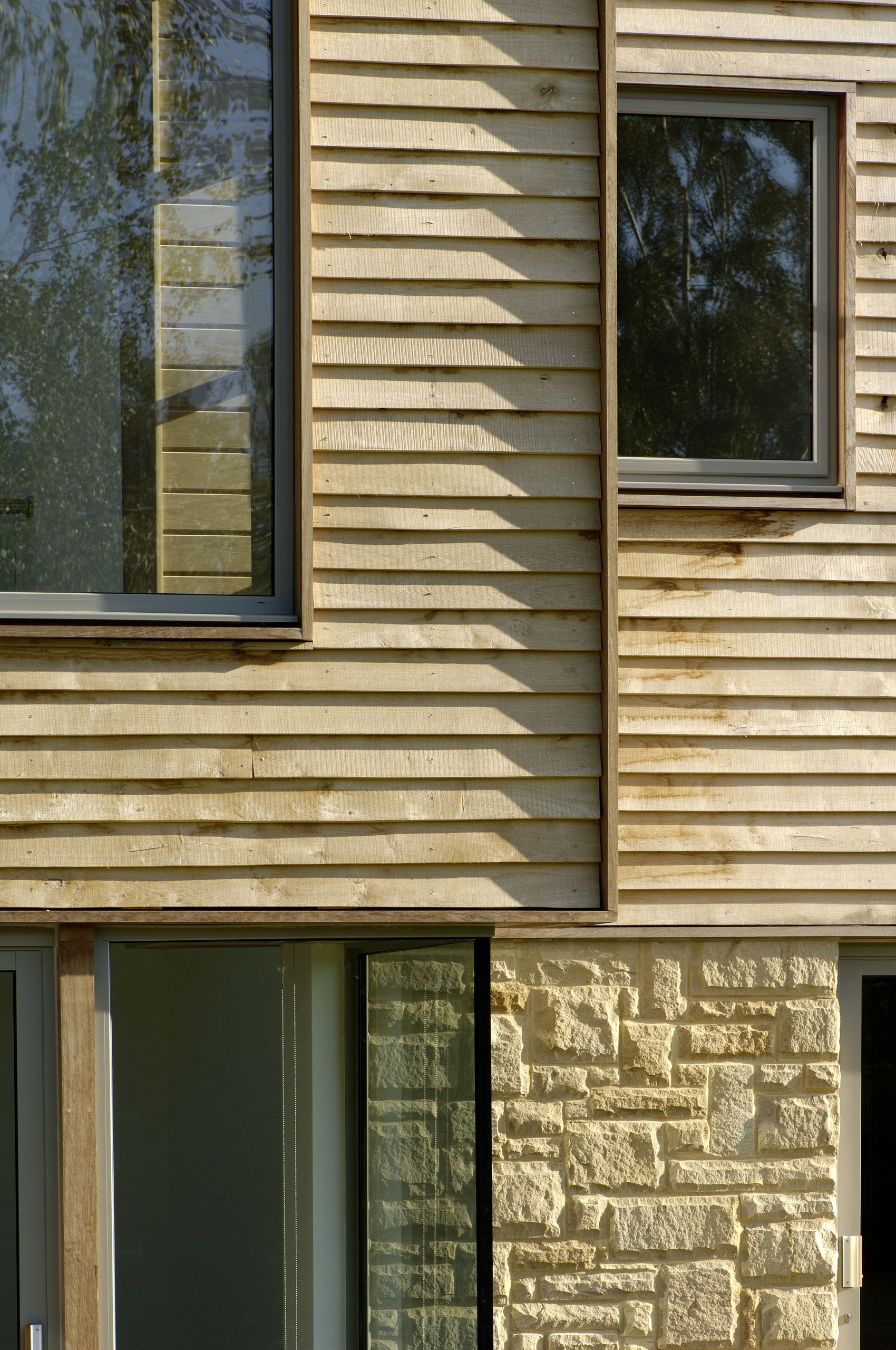 Oak cladding with local rustic stone provide a warm palette to soften the crisp, contemporary lines.